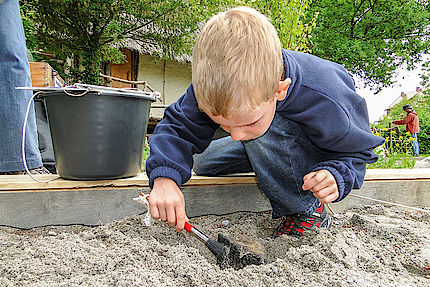 Junge beim archäologischen Graben mit Pinsel im Sand